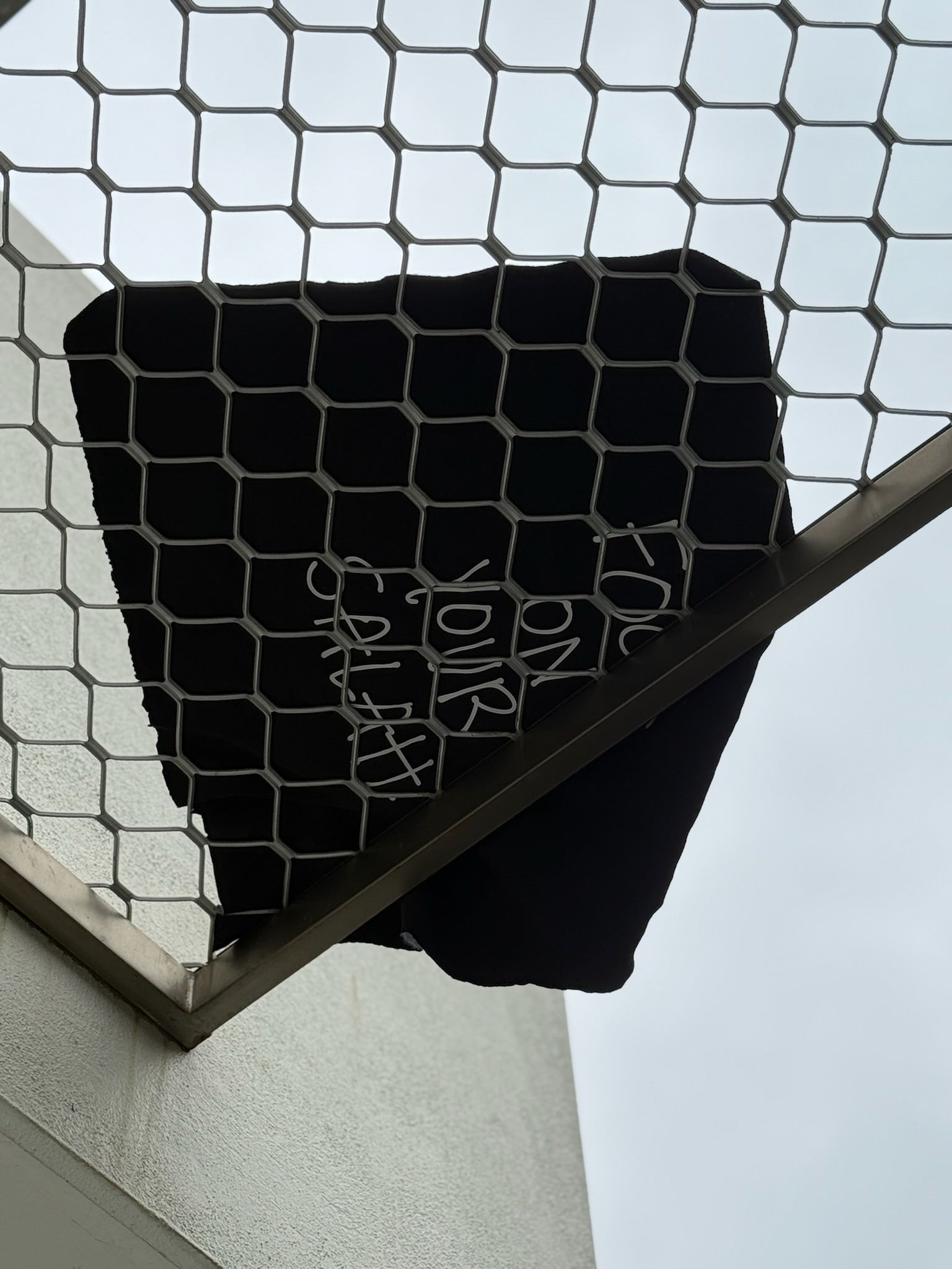 Black tshirt with text draped over a metal frame against a light background