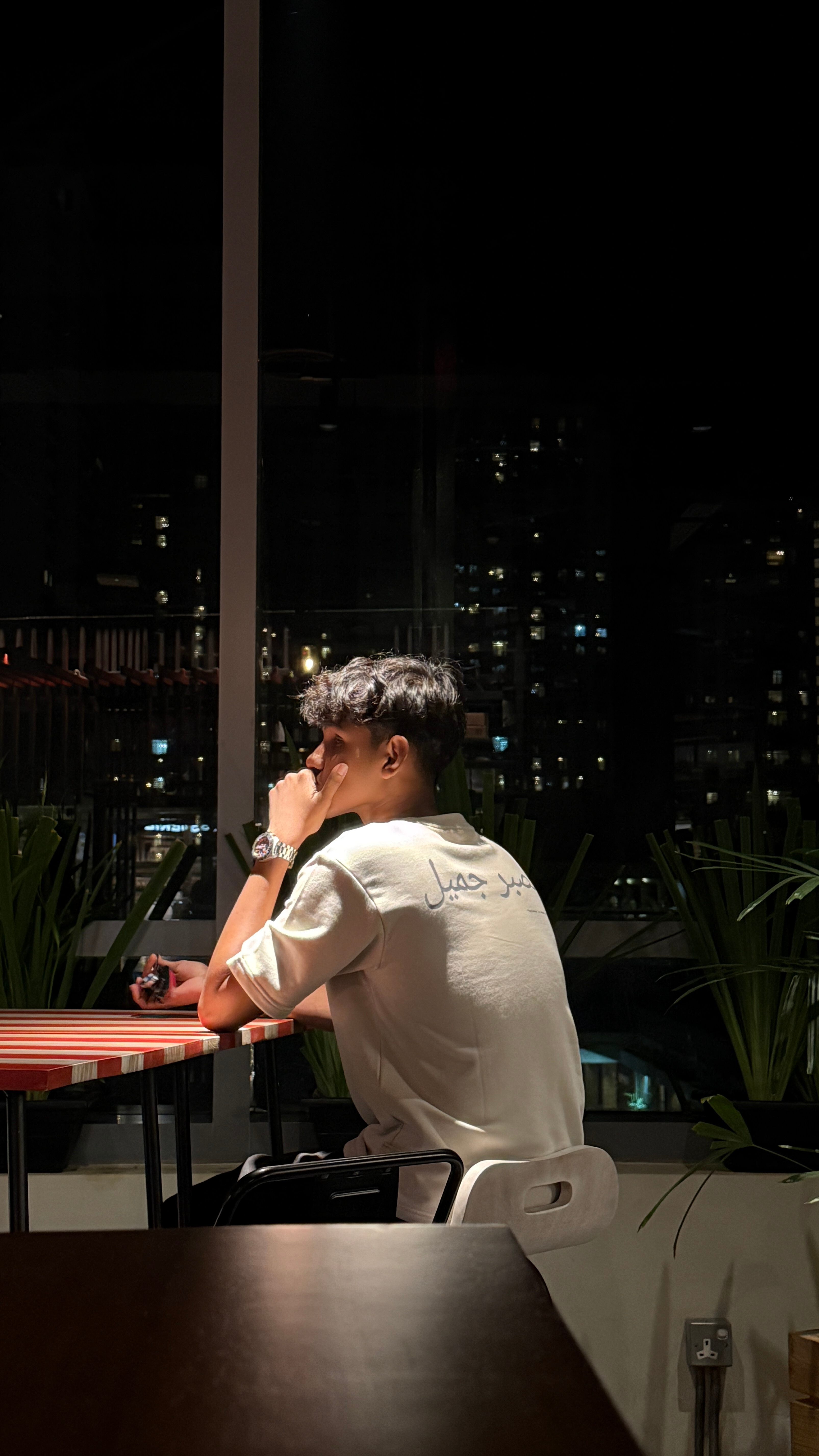 Person sitting at a table with a cityscape view at night